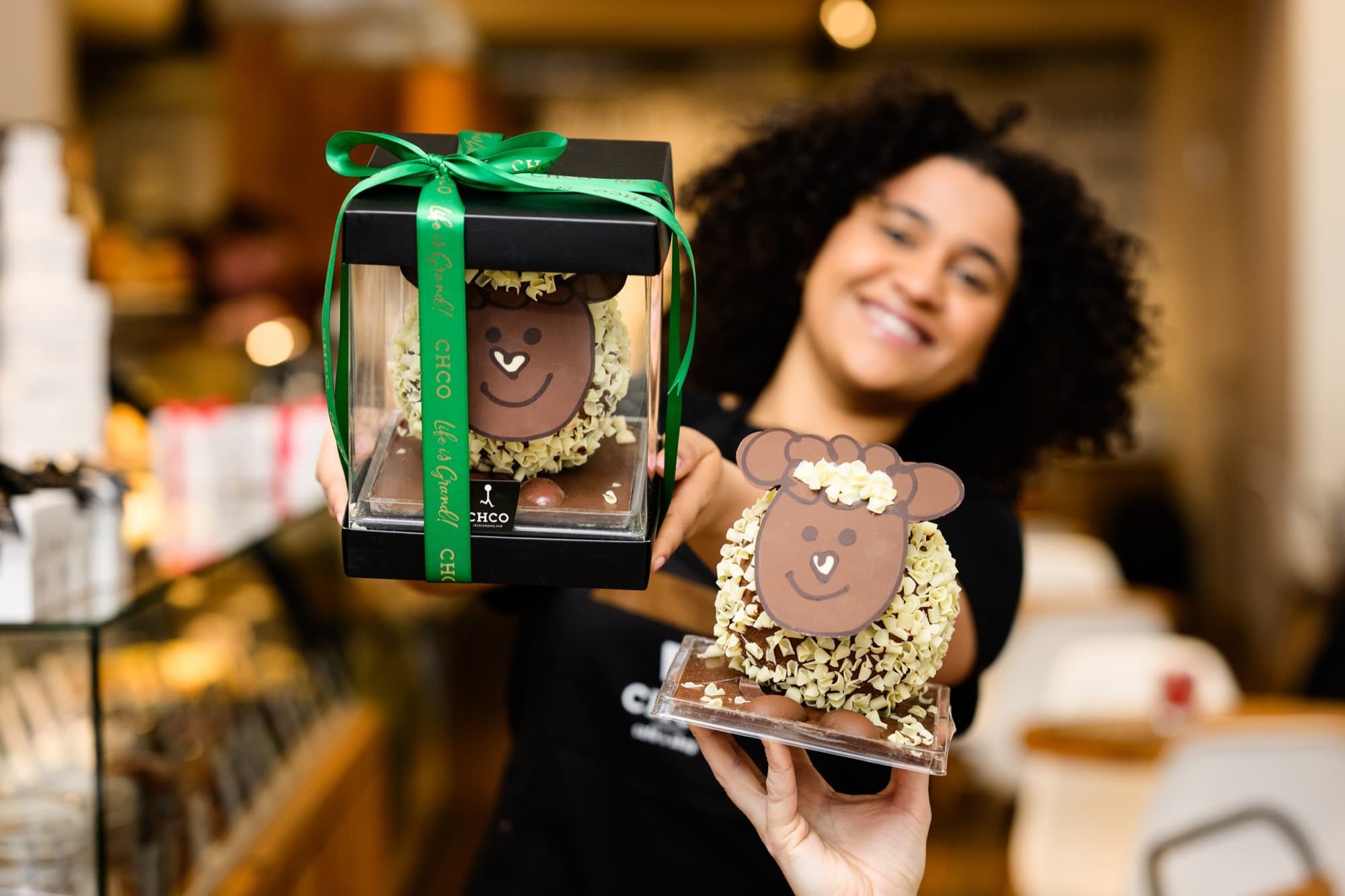 Medewerker toont handgemaakte chocoladefiguren in een geschenkverpakking